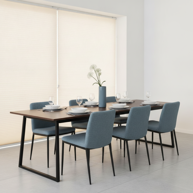 A modern dining room with a rectangular dining table and chairs. Warm cream cellular honeycomb blinds cover a window, filteri